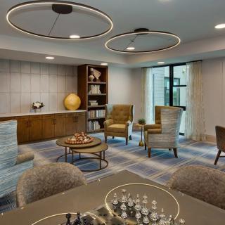 A modern lounge area featuring stylish seating, a chessboard on the table, and decorative lighting.