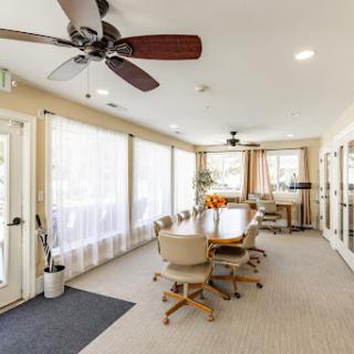 A bright and spacious meeting room featuring a large table surrounded by comfortable chairs, enhanced by natural light from expansive windows.