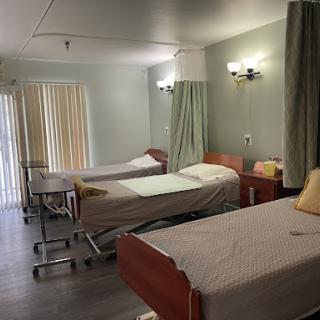 A view of a hospital patient room with multiple beds and soft lighting.