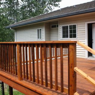 A wooden deck with a railing attached to the exterior of a house.