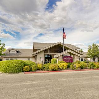 A welcoming building with an American flag, surrounded by greenery and under a cloudy sky.