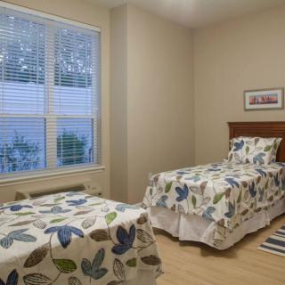 A cozy bedroom with two twin beds featuring decorative bedding and a large window letting in natural light.