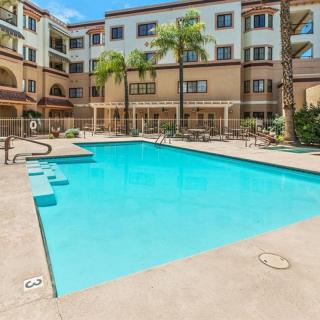A hotel courtyard featuring a large outdoor swimming pool surrounded by palm trees.