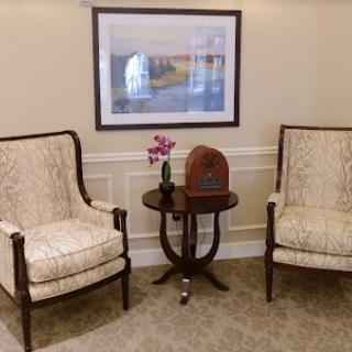 A cozy seating area featuring elegant chairs, a decorative table with flowers, and wall art.