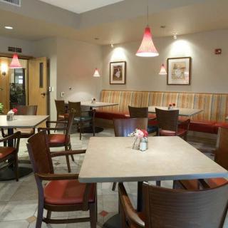 A cozy restaurant interior with neatly arranged tables and chairs, warm lighting, and subtle decor.