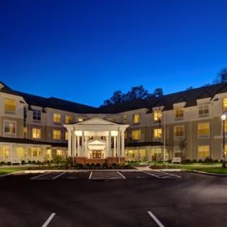 A well-lit hotel building at night with a spacious parking lot.