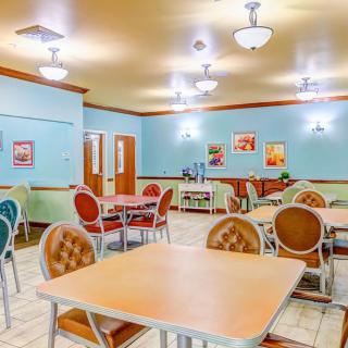 An empty dining room with colorful chairs and tables arranged neatly.