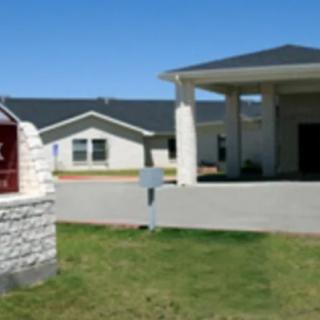 A building entrance with a driveway and a sign in the foreground.