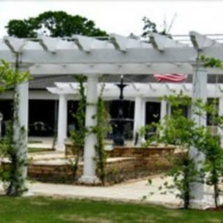 A scenic outdoor garden with a white pergola and lush greenery.