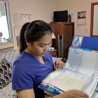 A healthcare professional in blue scrubs reviewing medical records in an office setting.