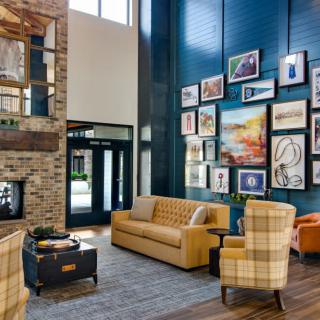 A stylish living room with a mix of modern and cozy elements, featuring a comfortable sofa, armchair, fireplace, and an artistic wall display.