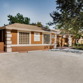 A commercial building with a spacious driveway and surrounding trees.