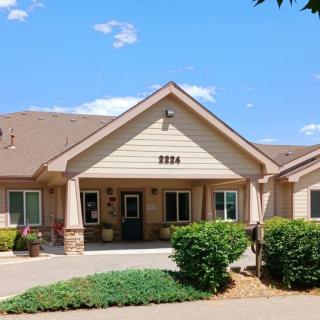 A building with a welcoming entrance, surrounded by landscaping and set against a clear blue sky.