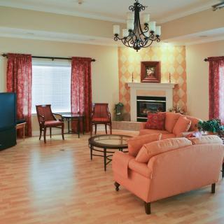 A well-furnished living room with a cozy sofa, elegant chandelier, and a warm fireplace.