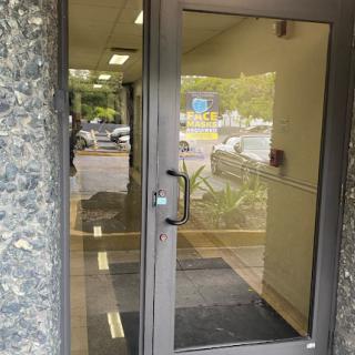 A view of a glass door leading into a building, showcasing reflections and the surrounding area.