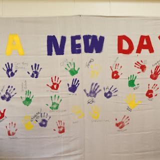 A vibrant expression of unity and creativity, showcasing handprints and the message 'A NEW DAY'.
