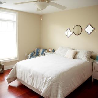 A minimalist bedroom with a neatly made bed, white linens, and simple wall decor.