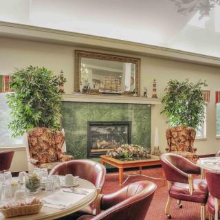 A cozy dining area featuring a fireplace, surrounded by elegant chairs and tables with decorative plants.