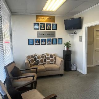 A cozy waiting room featuring a comfortable sofa, chairs, wall art, and a television.