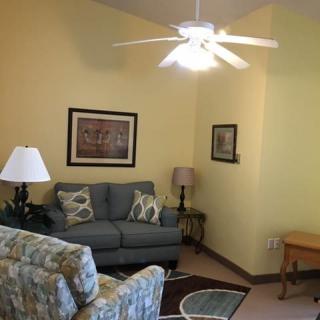 A cozy living room featuring a sofa, artwork on the walls, and a ceiling fan.