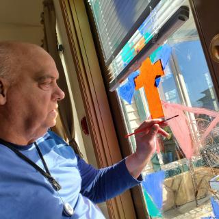 A man painting on a window in an indoor setting.