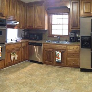 A spacious kitchen featuring wooden cabinets, stainless steel appliances, and a large window above the sink.