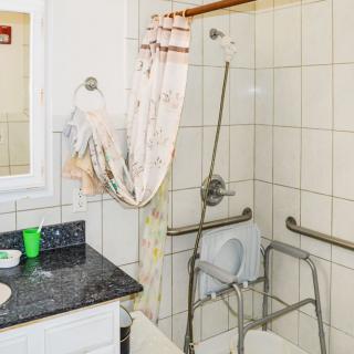 An accessible bathroom with a shower, equipped with grab bars and a shower chair.