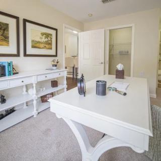 A bright and modern home office with a white desk and bookshelves, complemented by framed artwork on the walls.