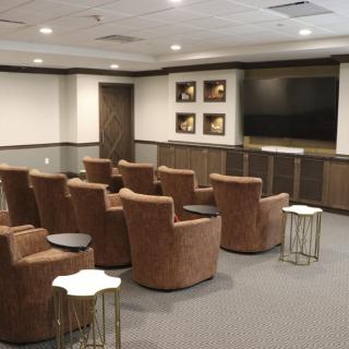 A cozy home theater room with comfortable chairs arranged in rows facing a large TV screen.