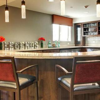 A modern bar interior with wooden accents, featuring pendant lighting and comfortable seating.