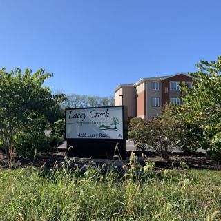 A sign for Cary Crest Apartments with a building and trees in the background.