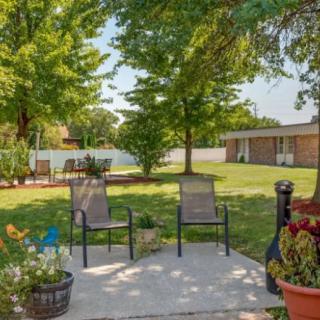 A peaceful backyard patio area with two chairs, surrounded by a well-maintained lawn and lush trees.