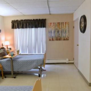 A well-lit hospital room with a single bed, window, and furnishings.