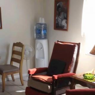 A cozy room featuring a red armchair, a water cooler, and some decor on the walls.
