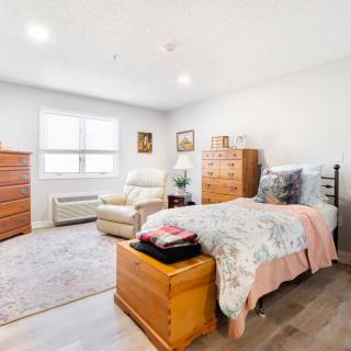 A cozy bedroom featuring a bed, dresser, and comfortable seating area.