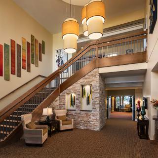 A modern lobby interior featuring a staircase with wooden railings, comfortable seating arrangements, and elegant lighting fixtures.