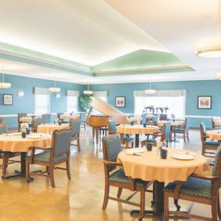 A spacious dining area with neatly set tables and a grand piano.