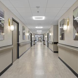A well-lit hospital corridor with doors on both sides.