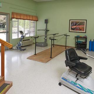 A physical therapy room equipped with exercise machines and parallel bars for rehabilitation exercises.