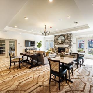 A spacious and elegantly designed living room with a dining area, featuring modern furniture, a fireplace, and a chandelier.