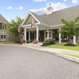 A well-maintained building entrance with flags and neatly landscaped surroundings.