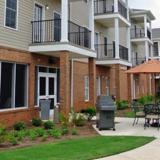Modern apartment building with outdoor patio and grill area.