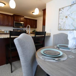A modern dining area with a set table and a view of the kitchen.
