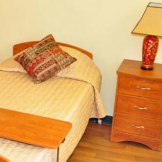 A cozy bedroom setup with a single bed, wooden side table, and decorative lamp.