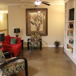 A cozy living room with a red sofa, floral armchairs, and a built-in bookshelf.