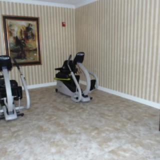 A small gym room with exercise equipment and striped wallpaper.