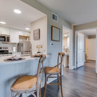 A modern kitchen with a counter and bar stools, featuring stainless steel appliances.