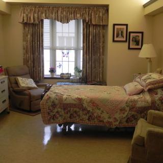 A cozy bedroom with a bed, armchair, and window with curtains.
