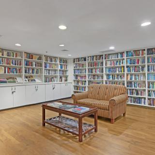 A cozy library room with floor-to-ceiling bookshelves, a comfortable couch, and a wooden coffee table.