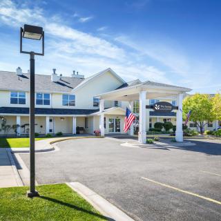 A daytime view of a hotel building with an entrance and parking lot.